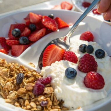 A side-by-side comparison of cottage cheese with fruits and Greek yogurt parfait, highlighting their textures and toppings.
