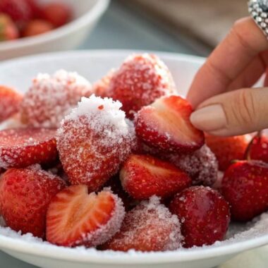 frosted strawberry from a white plate, surrounded by vibrant frozen strawberries.