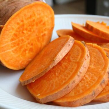 A vibrant close-up of an orange sweet potato sliced open, showcasing its rich color and texture.