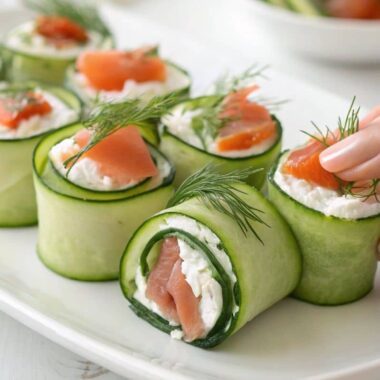 Close-up of Persian cucumber wraps with cream cheese, smoked salmon, and dill on a white plate.