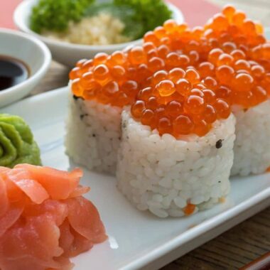 Close-up of salmon roe sushi with wasabi, soy sauce, and pickled ginger on the side