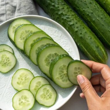 Featured image showing Persian and regular cucumbers with slices on a white plate.